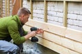Construction worker installing new wooden planks on house facade Royalty Free Stock Photo