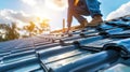 Construction worker installing tile roofing with safety gear at sunset. Royalty Free Stock Photo