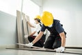 Construction worker installs laminate board on floor to renovate house. Asian builder man and woman wear safety helmet and