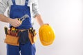 Construction worker with instrument, hard hat and tool belt on light background, closeup Royalty Free Stock Photo