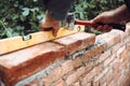 Professional construction worker laying bricks and building brick walls in industrial site. Detail of hand adjusting bricks Royalty Free Stock Photo