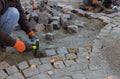 Construction worker laying granite cubes stone pavement on the road