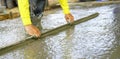 Construction worker leveling wet concrete floor with a trowel at construction site. Construction worker working with ready-mix Royalty Free Stock Photo