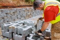 Construction worker lifts concrete block and places it on retaining wall after lifting it.