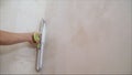 Worker aligns the wall with a spatula and putty. Construction worker with a long spatula plastering a wall Royalty Free Stock Photo
