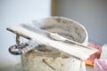 Construction worker with long trowel plastering a wall. Close-up of concrete.