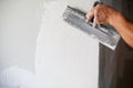 Construction worker with long trowel plastering a wall. Royalty Free Stock Photo