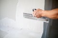 Construction worker with long trowel plastering a wall. Royalty Free Stock Photo