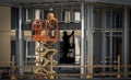 A construction worker on a manlift with another worker in shadow in the background Royalty Free Stock Photo