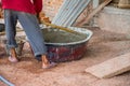 Construction worker manually mixing concrete in mixer tray