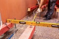 Construction worker measures distance between wooden blocks on the studs for lifting up floor due installing plumbin Royalty Free Stock Photo