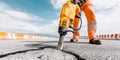 Construction worker operating a jackhammer, breaking asphalt on road for repair and maintenance Royalty Free Stock Photo