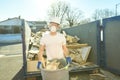 Construction Worker outside of house put old renovation material on big conteiner Royalty Free Stock Photo