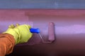 Construction worker painting conduit to protect against rust