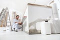 Construction worker plasterer man looks at the spirit level and checks the wall in building site of home renovation with tools and Royalty Free Stock Photo