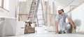 Construction worker plasterer man measuring wall with measure tape in building site of home renovation with tools and building Royalty Free Stock Photo