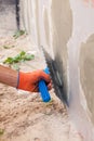 Construction worker plastering a wall and house foundation with trowel. Royalty Free Stock Photo