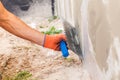 Construction worker plastering a wall and house foundation with trowel.