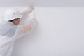 A construction worker in protective clothing and a hard hat, glues paint tape to create a multi-colored interior, on a white wall Royalty Free Stock Photo
