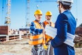 Construction worker in protective uniform shaking hands with businessman