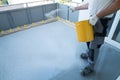 Construction worker renovates balcony floor and spreads chip floor covering on resin and glue coating before applaying water