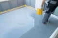 Construction worker renovates balcony floor and spreads chip floor covering on resin and glue coating before applying water