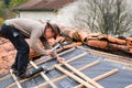 Construction worker fixing with a hammer and nails a wood cleat for the implementation of the infrastructure supporting the tiles Royalty Free Stock Photo