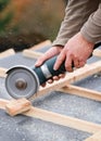 Construction worker on a renovation roof cutting a wood cleat with a disker for building the tile-friendly infrastructure Royalty Free Stock Photo