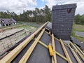 construction worker on a renovation roof covering it with tiles using hammer, crane and grinder