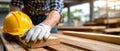 A construction worker rests their hand on a wooden surface, wearing gloves and a hard hat, in a vibrant, green setting Royalty Free Stock Photo