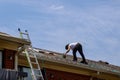 Construction worker roofer builder on roof structure applying asphalt shingles roofing
