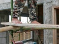 Construction worker`s bare feet standing on a wood plank on bamboo scaffolds that are installed around the constructing house -