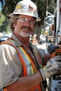 Construction worker in safety gear operating a power drill at a bustling construction site Royalty Free Stock Photo