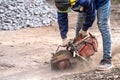 Construction worker in safety glasses and noise-canceling headphones at work. Cutting concrete floor for cable laying with a Royalty Free Stock Photo