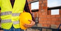 Construction worker on site zone. Worker holding hard hat and staying in front of the building zone. Worker on the work zone. Royalty Free Stock Photo