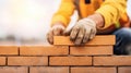 A construction worker skillfully lays bricks, creating a sturdy wall amidst a blurred backdrop of activity Royalty Free Stock Photo