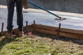 Construction Worker Smoothing Wet Cement With Long Handled Edger Tool