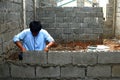 Construction worker stacks hollow blocks to build wall at construction of residential house