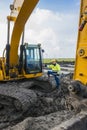 Construction worker standing proudly next to his excavator