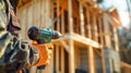 A construction worker stands ready with an electric drill at a wooden house construction site, surrounded by the framework of the Royalty Free Stock Photo