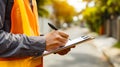Construction worker taking notes outdoors in a sunny residential area Royalty Free Stock Photo