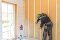 The worker makes finishing works of walls with a white wooden board, using laser line level. Building heat-insulating Royalty Free Stock Photo