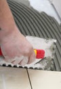 Construction worker is tiling at home, tile floor adhesive Royalty Free Stock Photo