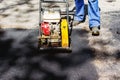 Construction worker in uniform operate vibratory plate compactor. Pothole repair process. Asphalt tamping machine operator. Pothol Royalty Free Stock Photo