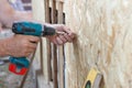 Construction worker use screwdriver to attach Wood Particle Board fiberboard to the wall. Royalty Free Stock Photo