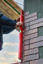 Construction worker use a spirit level to check decorative tiles on the facade of the building Royalty Free Stock Photo