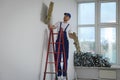 Construction worker with used glass wool on stepladder in room prepared for renovation