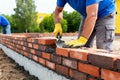 Bricklayer at work laying bricks with trowel and mortar to build a wall Royalty Free Stock Photo