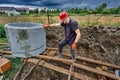 Construction worker uses winch to move concrete ring along sloping wooden deck during installation of septic tank. Royalty Free Stock Photo