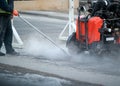 Construction worker using an asphalt saw cutting machine to excavate street